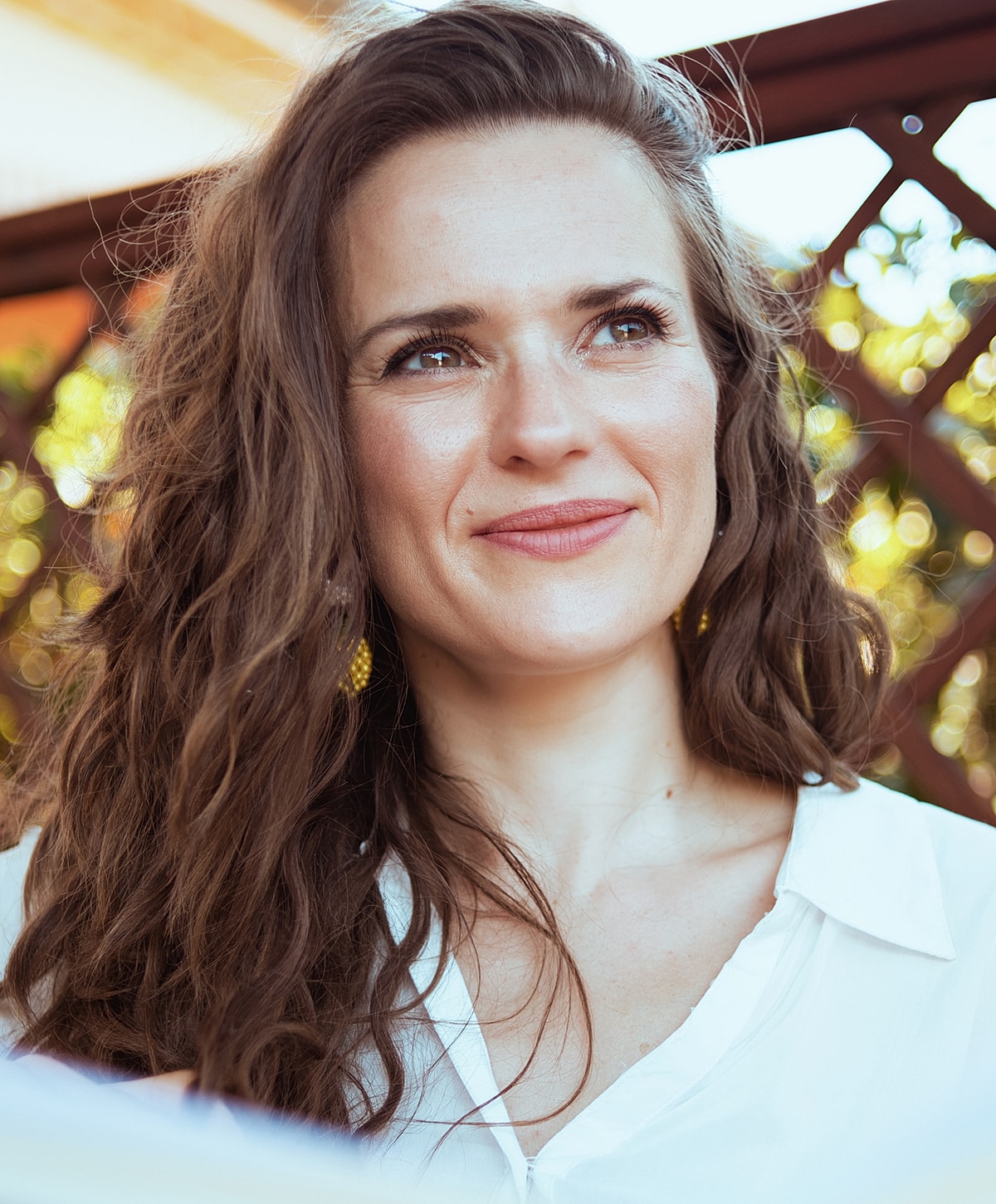 Smiling woman with wavy hair outdoors.
