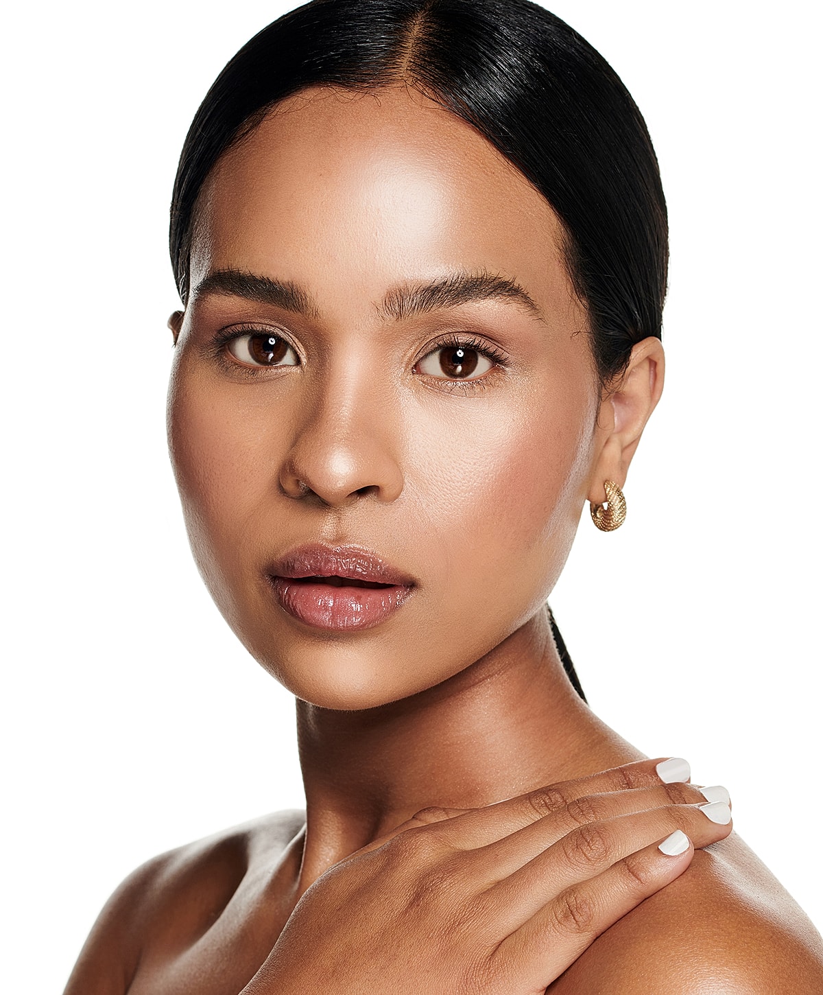 Smiling woman with natural makeup and gold earrings.