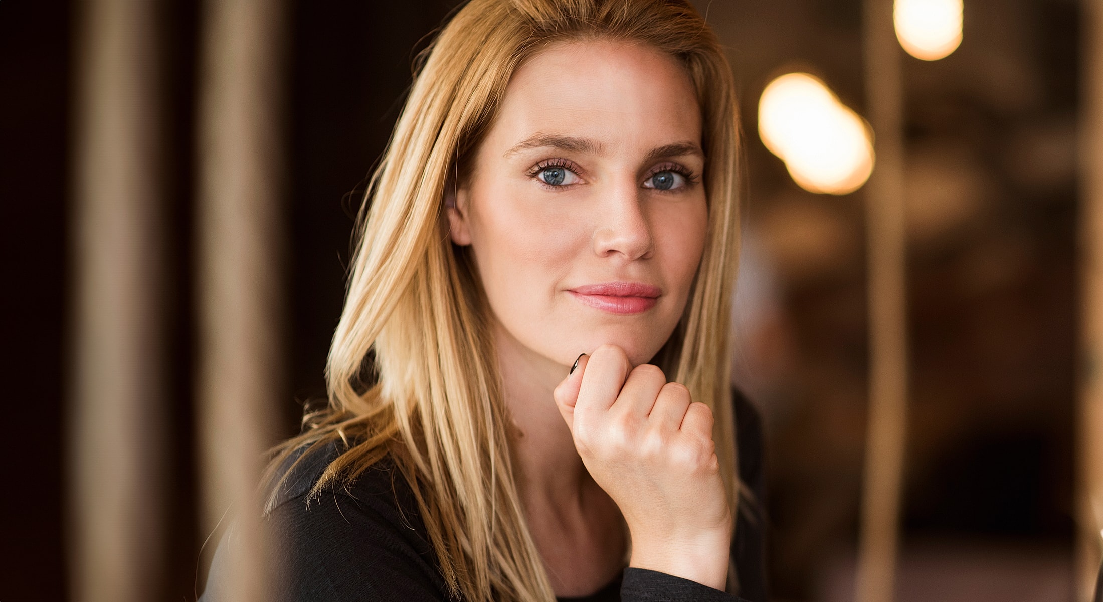 Woman with blonde hair, thoughtful expression indoors.